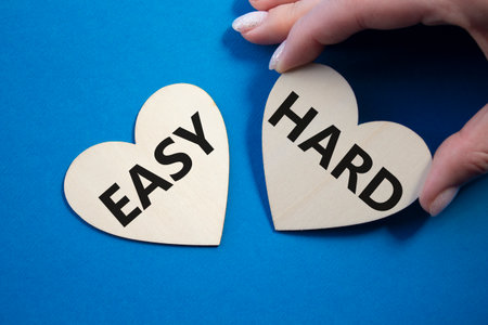 Easy or Hard symbol. Concept word Easy or Hard on wooden hearts. Businessman hand. Beautiful blue background. Business and Easy or Hard concept. Copy spaceの写真素材