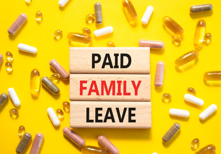 Paid Family Leave symbol. Concept words Paid Family Leave on wooden blocks. Beautiful yellow...