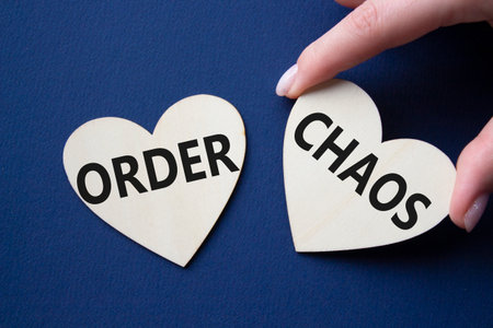 Chaos or Order symbol. Concept word Chaos or Order on wooden hearts. Businessman hand. Beautiful deep blue background. Business and Chaos or Order concept. Copy spaceの写真素材