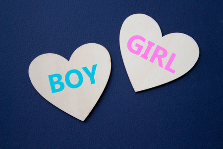 Boy or Girl symbol. Concept word Boy or Girl on wooden hearts. Beautiful deep blue background. Gender and Boy or Girl concept. Copy spaceの写真素材