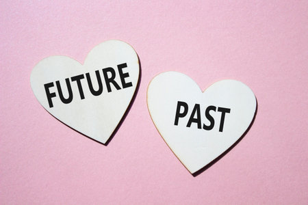 Future or Past symbol. Concept word Future or Past on wooden hearts. Beautiful pink background. Business and Future or Past concept. Copy spaceの写真素材