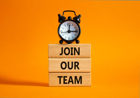 Join our team symbol. Wooden blocks with words Join our team. Beautiful orange background with alarm...