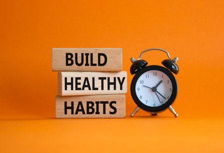 Healthy habits symbol. Concept word Build Healthy habits on wooden blocks with alarm clock....