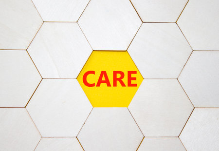 Care symbol. Concept word Care on wooden comb puzzle. Beautiful yellow background. Business and Care...