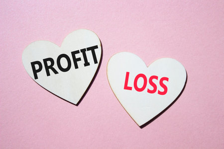 Profit or Loss symbol. Concept word Profit or Loss on wooden hearts. Beautiful pink background. Business and Profit or Loss concept. Copy spaceの写真素材