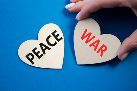 War or Peace symbol. Concept word War or Peace on wooden hearts. Businessman hand. Beautiful blue background. Business and War or Peace concept. Copy spaceの写真素材