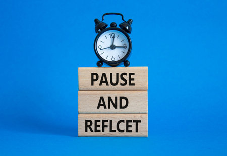 Pause and Reflect symbol. Concept words Pause and Reflect on wooden blocks. Beautiful blue...