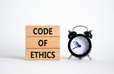 Code of ethics symbol. Concept words Code of ethics on wooden blocks with alarm clock. Beautiful white background. Business and Code of ethics concept. Copy space.の写真素材