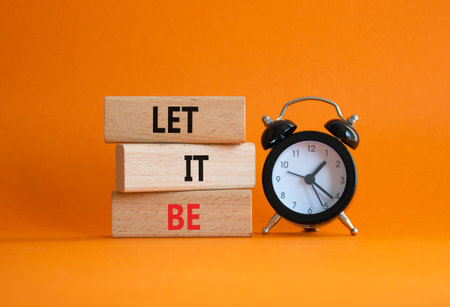 Let it be symbol. Concept words Let it be on wooden blocks. Beautiful orange background with alarm...