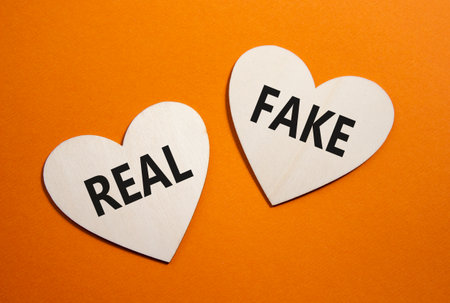 Real or Fake symbol. Concept word Real or Fake on wooden hearts. Beautiful orange background. Business and Real or Fake concept. Copy spaceの写真素材