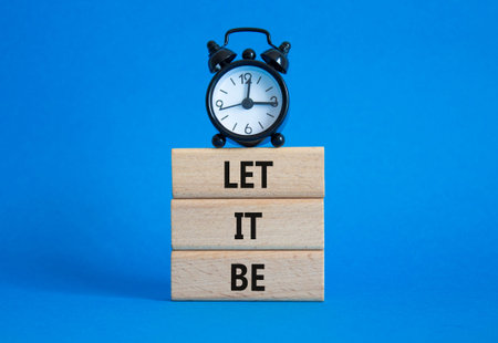 Let it be symbol. Concept words Let it be on wooden blocks. Beautiful blue background with alarm...