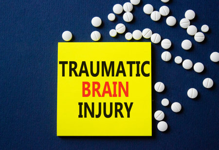 Traumatic Brain Injury symbol. Concept words Traumatic Brain Injury on yellow note. Beautiful deep...