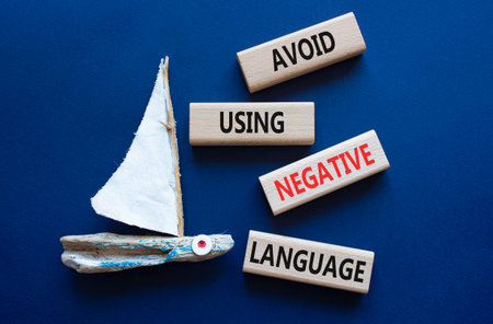 Wooden blocks with words Avoid using Negative Language. Beautiful deep blue background with boat. Business and Avoid using Negative Language concept. Copy space.の写真素材
