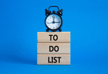 To Do List symbol. Concept words To Do List on wooden blocks. Beautiful blue background with alarm...