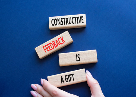 Feedback symbol. Wooden blocks with words Constructive Feedback is a gift. Businessman hand....