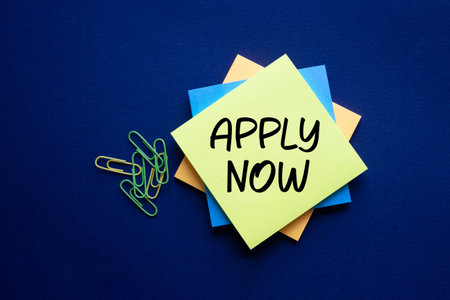 Apply now symbol. Concept word Apply now on sticky note. Beautiful deep blue background. Business...
