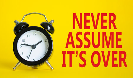 Never assume it is over symbol. Beautiful yellow background with alarm clock. Business and Never assume it is over concept. Copy space.の写真素材