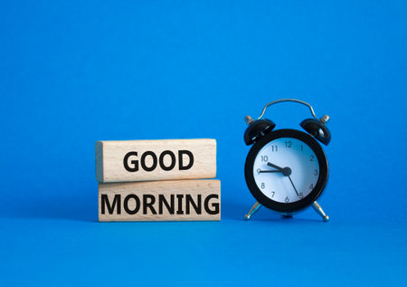 Good Morning symbol. Concept word Good Morning on wooden blocks. Beautiful blue background with alarm clock. Business and Good Morning concept. Copy spaceの写真素材
