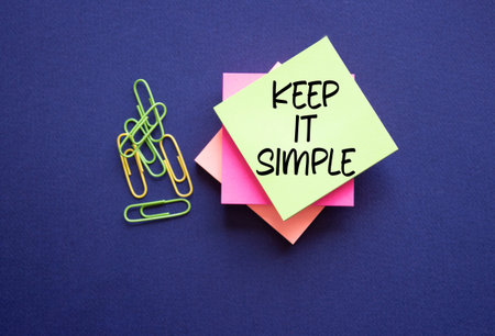 Keep it Simple symbol. Concept words Keep it Simple on sticky notes. Beautiful deep blue background....