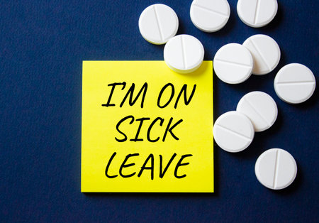 Sick leave symbol. Concept word I am on sick leave on yellow note. Beautiful deep blue background with pills. Medicine and I am on sick leave concept. Copy spaceの写真素材