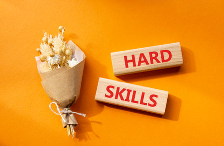 Hard skills symbol. Wooden blocks with words Hard skills. Beautiful orange background with bouquet of flowers. Business and Hard skills concept. Copy space.の写真素材