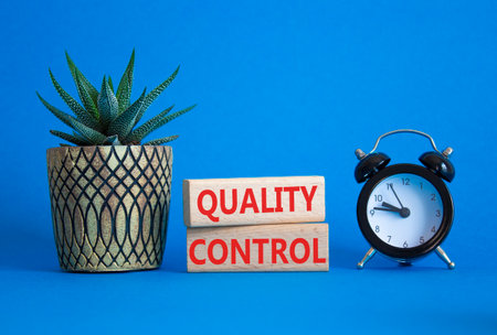 Quality Control symbol. Wooden blocks with words Quality Control. Beautiful blue background with alarm clock. Business and Quality Control concept. Copy space.の写真素材