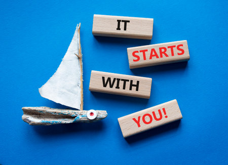 It starts with you symbol. Wooden blocks with words It starts with you. Beautiful blue background with boat. Business and It starts with you concept. Copy space.の写真素材