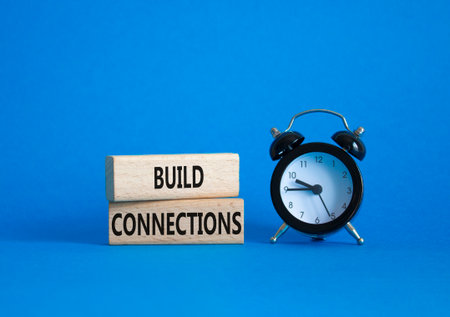 Build Connections symbol. Concept word Build Connections on wooden blocks. Beautiful blue background with alarm clock. Business and Build Connections concept. Copy spaceの写真素材