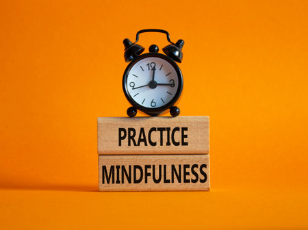 Practice Mindfulness symbol. Wooden blocks with words Practice Mindfulness. Beautiful orange background with alarm clock. Medical and Psychology and Practice Mindfulness concept. Copy space.の写真素材