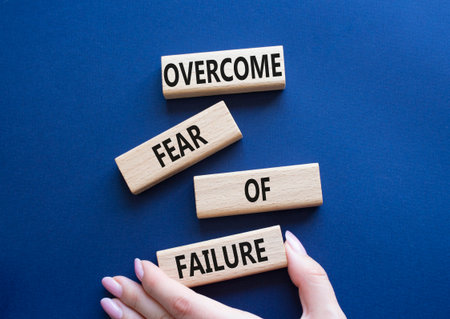 Fear of failure symbol. Concept words Overcome Fear of failure on wooden blocks. Beautiful deep blue background. Businessman hand. Business and Fear of failure concept. Copy space.の写真素材