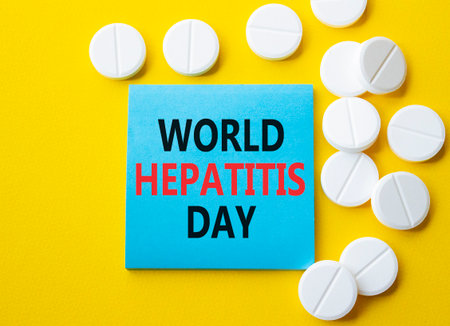 World Hepatitis Day symbol. Concept words World Hepatitis Day on blue note. Beautiful yellow background with pills. Healthcare and World Hepatitis Day concept. Copy space.の写真素材