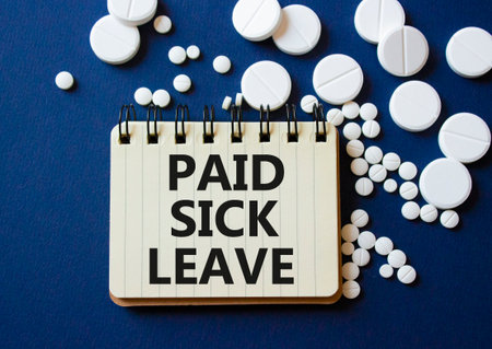 Paid Sick Leave symbol. Concept words Paid Sick Leave on notebook. Beautiful deep blue background with pills. Healthcare and Paid Sick Leave concept. Copy space.の写真素材