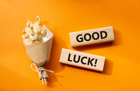 Good luck symbol. Wooden blocks with words Good luck. Beautiful orange background with bouquet of flowers. Business and Good luck concept. Copy space.の写真素材
