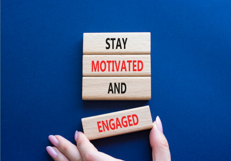 Stay Motivated and Engaged symbol. Concept words Stay Motivated and Engaged on wooden blocks. Beautiful deep blue background. Businessman hand. Business concept. Copy spaceの写真素材