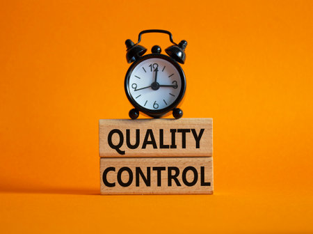 Quality Control symbol. Wooden blocks with words Quality Control. Beautiful orange background with alarm clock. Business and Quality Control concept. Copy space.の写真素材