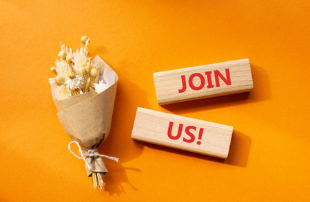 Join us symbol. Concept word Join us on wooden blocks. Beautiful orange background with bouquet of...