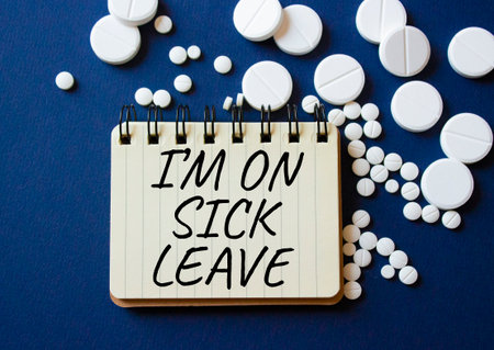 Sick leave symbol. Concept word I am on sick leave on notebook. Beautiful deep blue background with pills. Medicine and I am on sick leave concept. Copy spaceの写真素材
