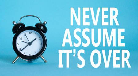 Never assume it is over symbol. Beautiful blue background with alarm clock. Business and Never assume it is over concept. Copy space.の写真素材