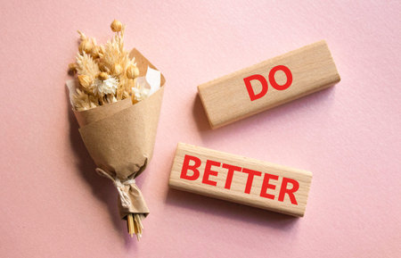 Do better symbol. Wooden blocks with words Do better. Beautiful pink background with bouquet of...