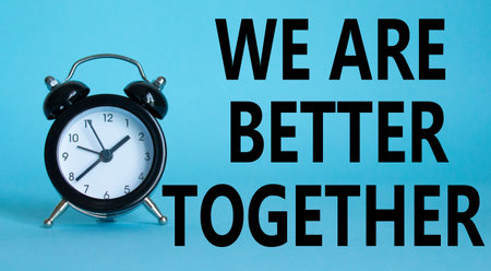 Beautiful blue background with alarm clock with words We are better together. Copy space.