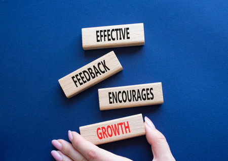 Feedback symbol. Wooden blocks with words Effective Feedback encourages growth. Businessman hand....