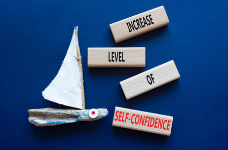 Wooden blocks with words Increase Level of Self-Confidence. Beautiful deep blue background with...