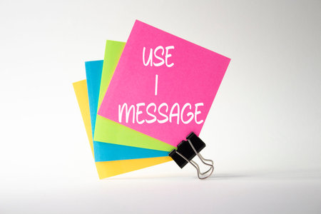 Use I message symbol. Pink sticky note with paper clips with words Use I message. Beautiful white...