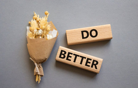 Do better symbol. Wooden blocks with words Do better. Beautiful gray background with bouquet of flowers. Business and Do better concept. Copy space.の写真素材
