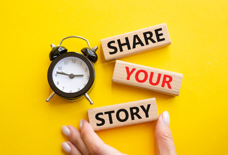 Share your story symbol. Wooden blocks with words Share your story. Businessman hand. Beautiful yellow background with alarm clock. Business and Share your story concept. Copy space.の写真素材