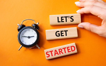 Lets get started symbol. Concept words Lets get started on wooden blocks. Businessman hand....
