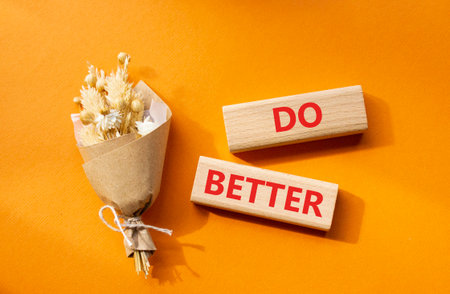Do better symbol. Wooden blocks with words Do better. Beautiful orange background with bouquet of flowers. Business and Do better concept. Copy space.の写真素材
