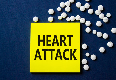Heart Attack symbol. Concept word Heart Attack on yellow note. Beautiful deep blue background with pills. Medicine and Heart Attack concept. Copy spaceの写真素材