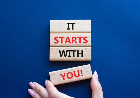 It starts with you symbol. Wooden blocks with words It starts with you. Beautiful deep blue background. Businessman hand. Business and It starts with you concept. Copy space.の写真素材