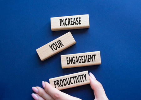 Productivity symbol. Wooden blocks with words Increase your Engagement Productivity. Beautiful deep blue background. Businessman hand. Business concept. Copy space.の写真素材